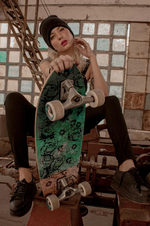 a young woman sitting on top of a skateboard, a colorized photo, trending on pexels, tattooed, indoor picture, camo, wheels