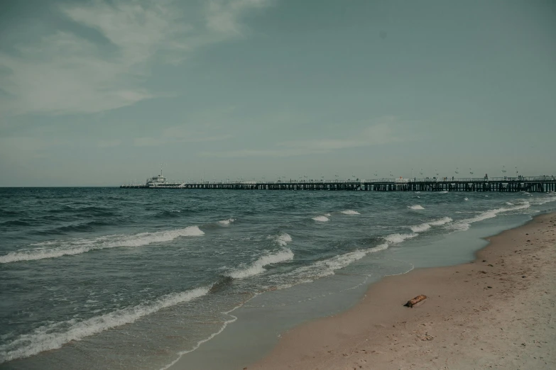 a large body of water next to a sandy beach, by Niko Henrichon, pexels contest winner, near a jetty, background image, listing image, faded colors