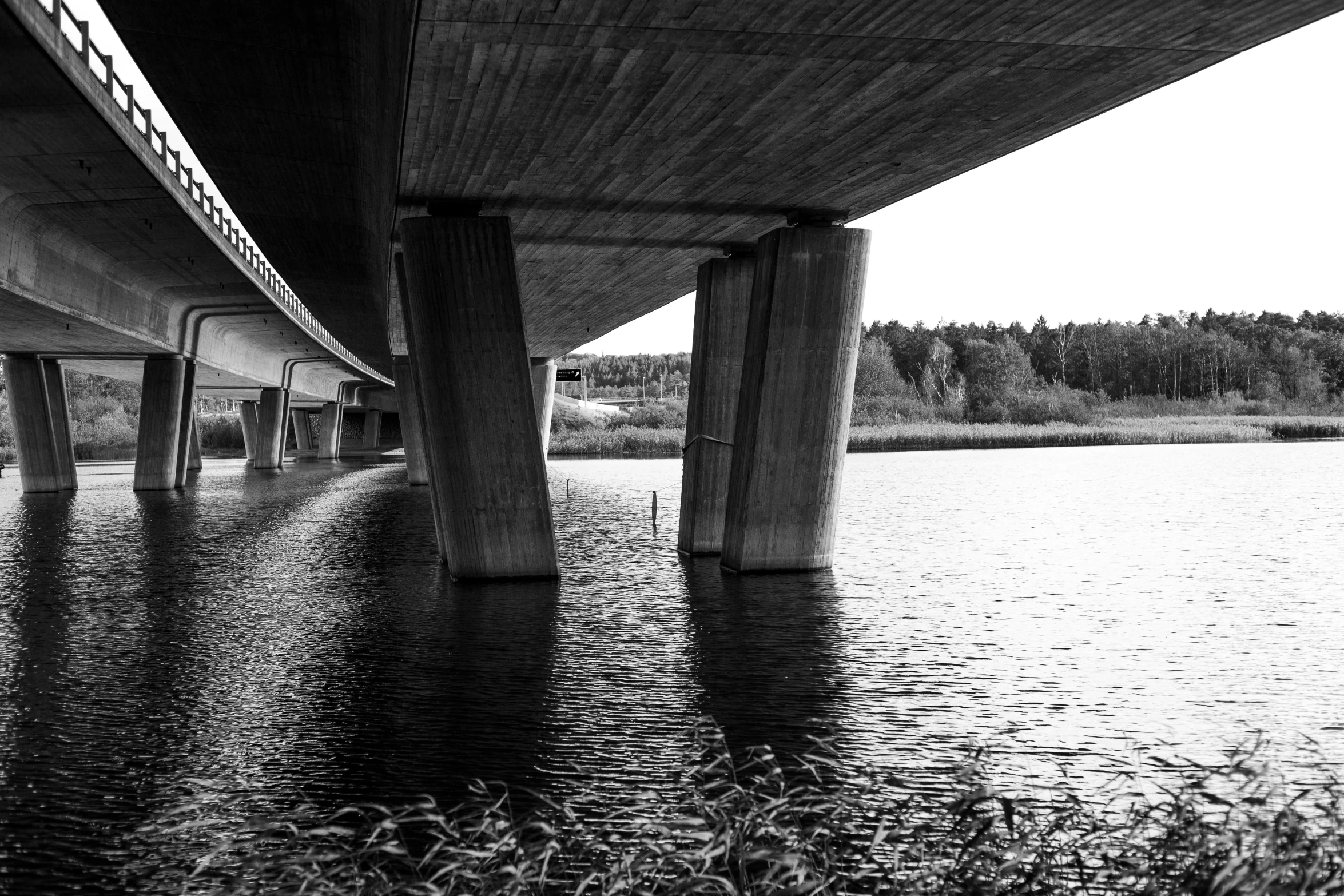 a black and white photo of a bridge over a body of water, by Peter Madsen, espoo, under bridge, highway, complex composition!!