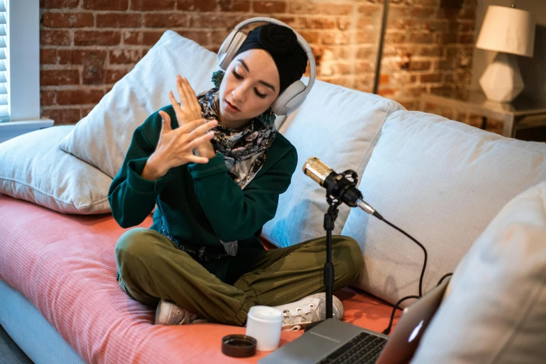 a woman sitting on a couch with headphones on, inspired by Maryam Hashemi, hurufiyya, holding microphone, feeds on everything, islamic, on a coffee table