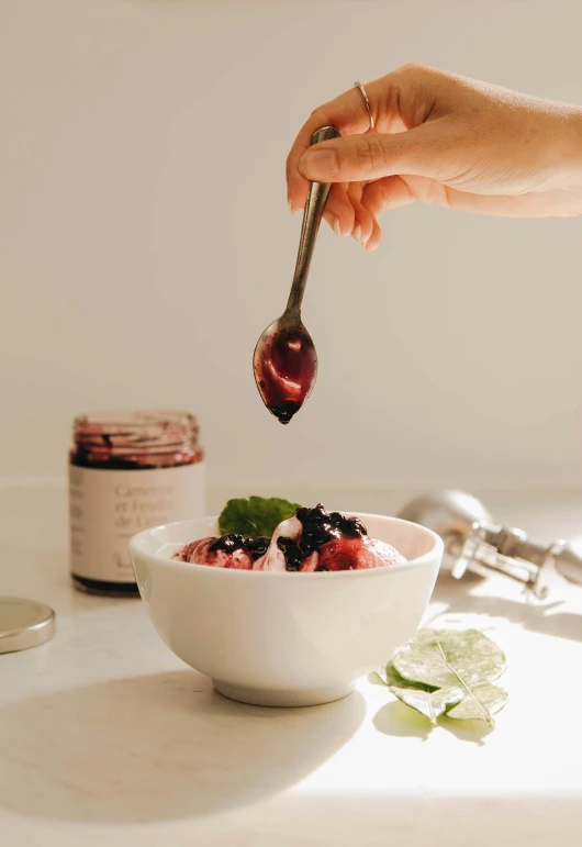 a person holding a spoon over a bowl of fruit, product image, infused with a dream, profile image, glaze