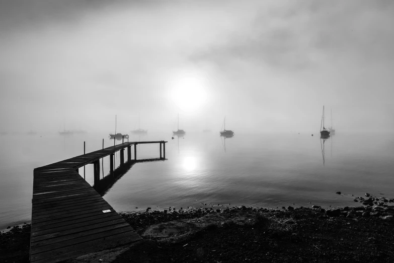 a black and white photo of a dock on a foggy day, a black and white photo, pexels, sailboats, morning sunrise, yellow mist, landscape photo