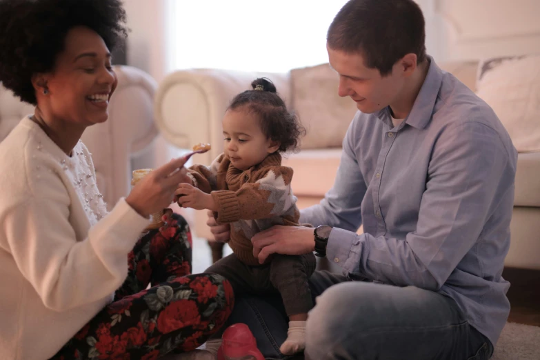 a man and woman sitting on the floor playing with a baby, pexels contest winner, avatar image, mixed race, holding an epée, small in size