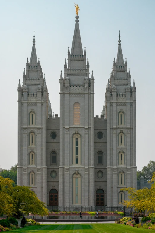 a large building sitting on top of a lush green field, a statue, cathedrals, utah, symmetrical!!, three towers