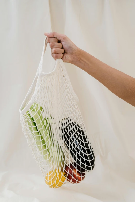 a person holding a net bag full of fruit, unsplash, plasticien, wearing white camisole, made of bamboo, full frame image, sports photo