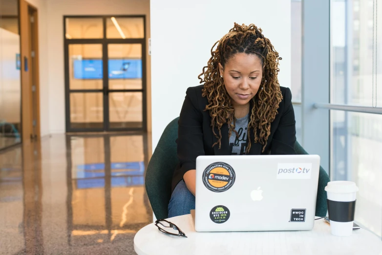 a woman sitting at a table with a laptop, a photo, by Stokely Webster, tech demo, justify contents center, profile image