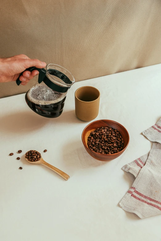 a person pouring a cup of coffee on top of a table, a still life, unsplash, ingredients on the table, tall shot, gravels around, gif