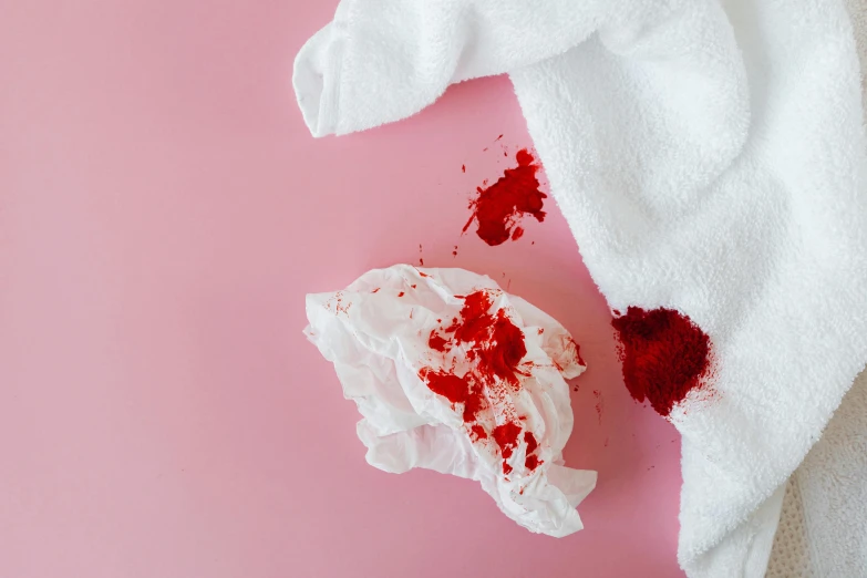 a white towel sitting on top of a pink surface, trending on pexels, happening, lots of blood, wipe out, on a white table, red cloth