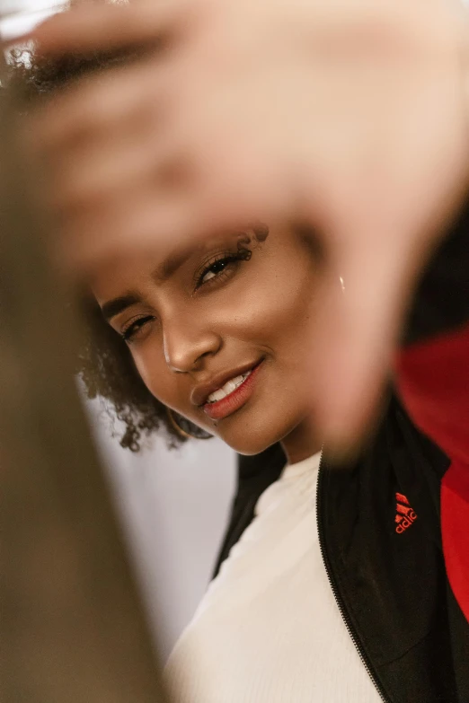 a close up of a person holding a cell phone, wearing adidas clothing, african ameera al taweel, shy looking down, wearing red jacket