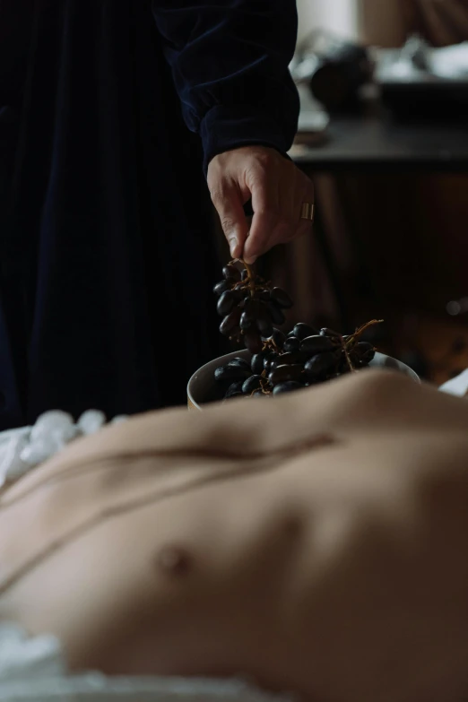 a person laying in a bed with a bunch of grapes, inspired by Caravaggio, unsplash, renaissance, still from the movie ex machina, belly button showing, apothecary, ( ( theatrical ) )
