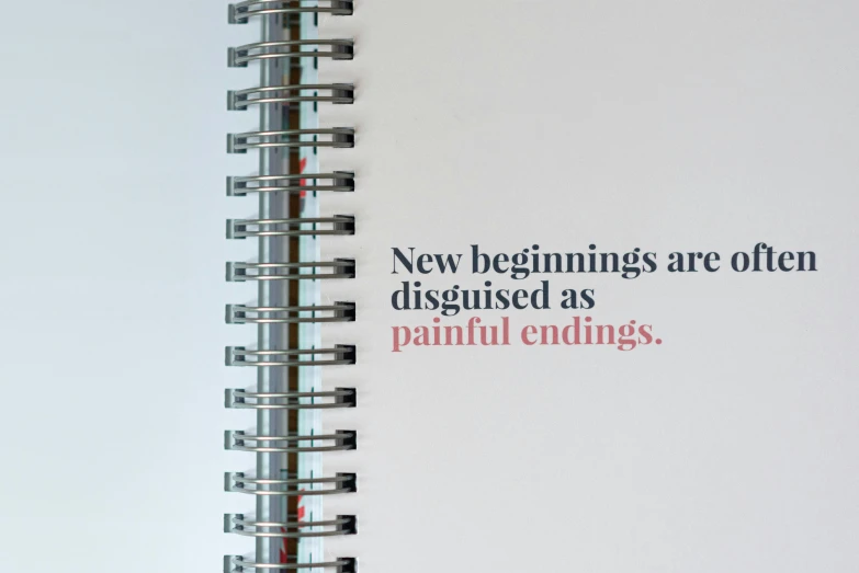 a spiral notebook with the words new beginnings are often disguised as painful endings, detail, for a catalogue, ad image, 0