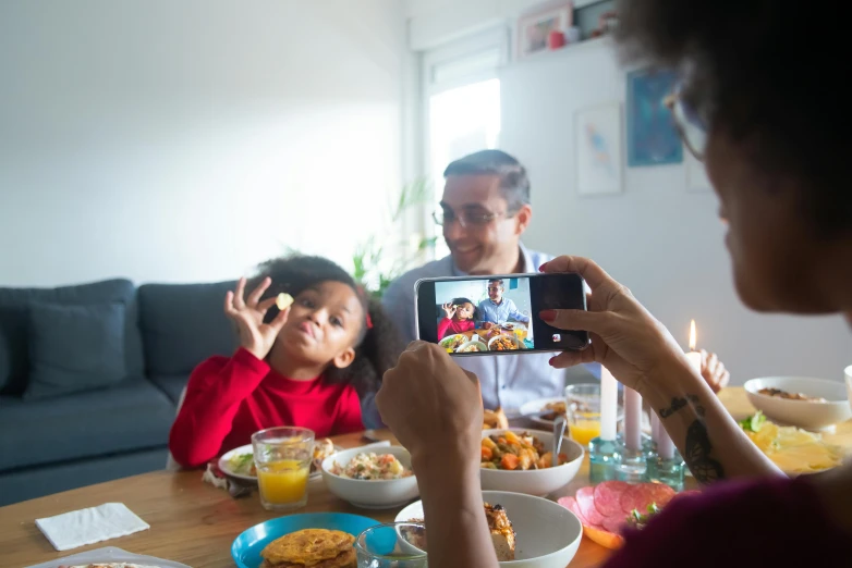 a woman taking a picture of a family at a dinner table, pexels contest winner, tiktok video, ashteroth, movie filmstill, smartphone footage