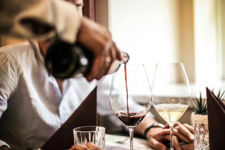 a group of people sitting at a table with wine glasses, pouring, up close, multiple stories, thumbnail