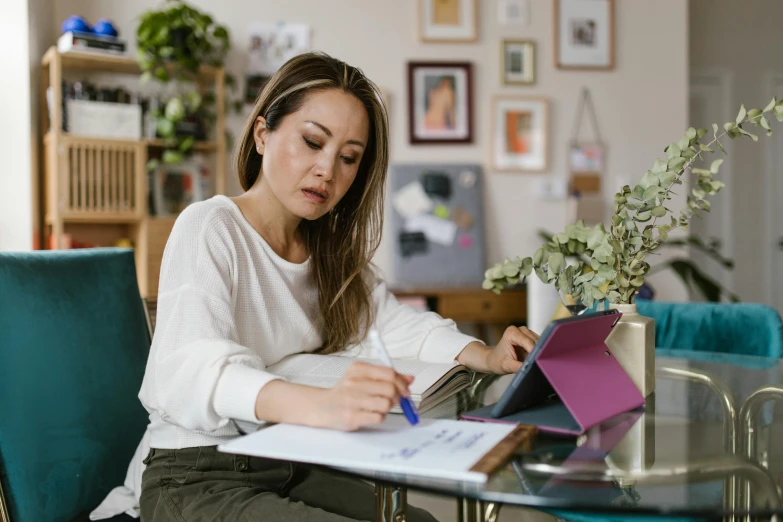 a woman sitting at a table working on a laptop, by Nicolette Macnamara, pexels contest winner, asian descent, holding pencil, avatar image, multiple stories