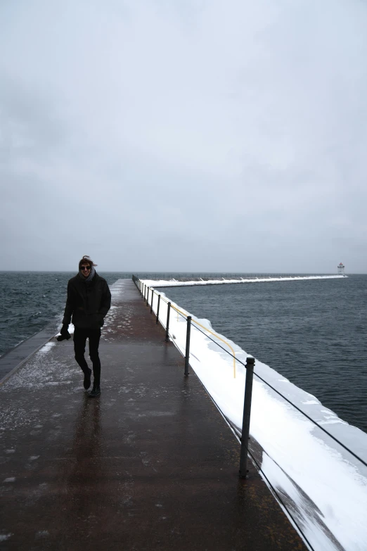 a person walking on a pier in the snow, by Christen Dalsgaard, happening, wall of water either side, covered!