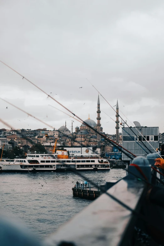 a group of people standing on top of a pier next to a body of water, by irakli nadar, pexels contest winner, hurufiyya, with beautiful mosques, ships in the harbor, grey, mixture turkish and russian