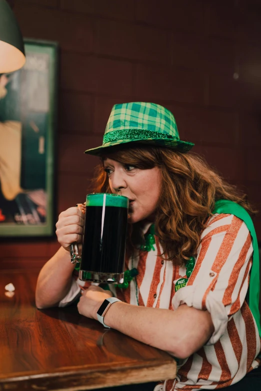 a woman sitting at a table with a glass of beer, wearing green tophat, irish genes, fan favorite, green and brown clothes