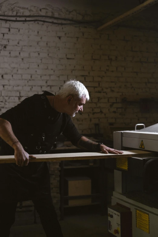 a man is working on a piece of wood, a woodcut, by Paul Bird, trending on unsplash, large format picture, cinematic still, man and machine, john pawson