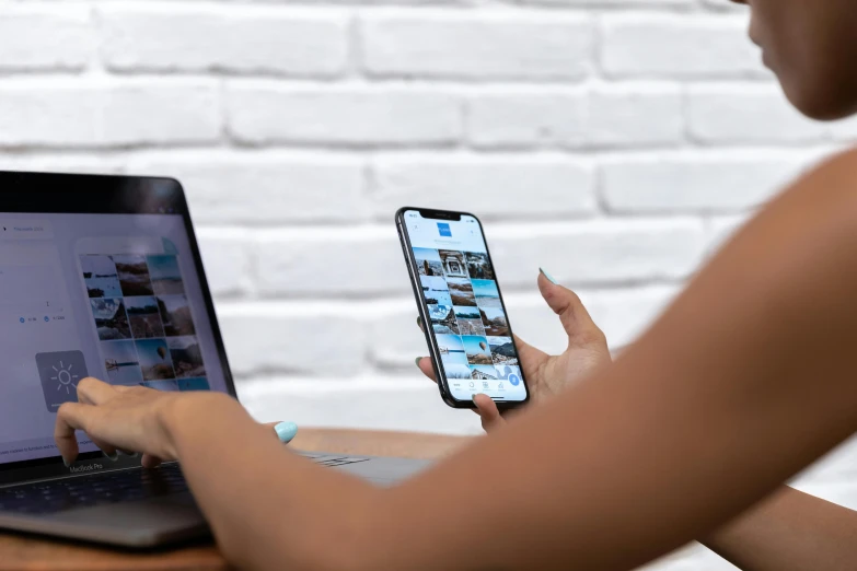 a woman sitting at a table with a laptop and a cell phone, a picture, trending on pexels, instagram post 4k, zoomed out, high quality photo, concept photo