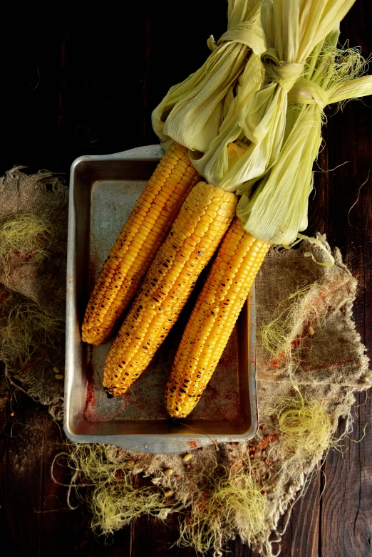 a tray filled with corn on top of a wooden table, charred, large cornicione, f / 2 0, detailed product shot