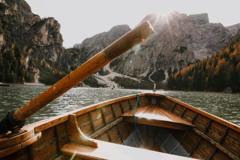 a boat on a lake with mountains in the background, pexels contest winner, sunlight glistening, dolomites in the background, on the bow, thumbnail