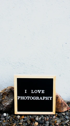 a sign that says i love photography next to a rock, unsplash, high quality photo, wood print, brown, foto