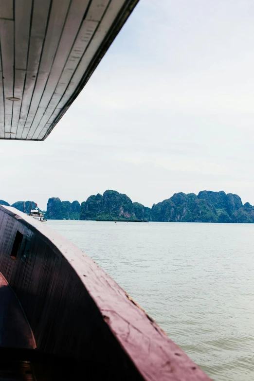 a boat on a body of water with mountains in the background, bao phan, ship interior, viewed from afar