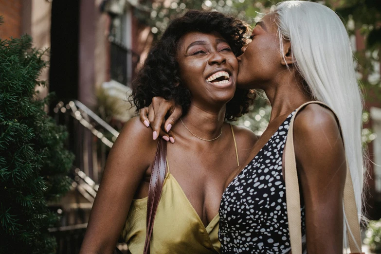 a couple of women standing next to each other, trending on pexels, happening, kissing smile, brown skin, a blond, iridescent skin