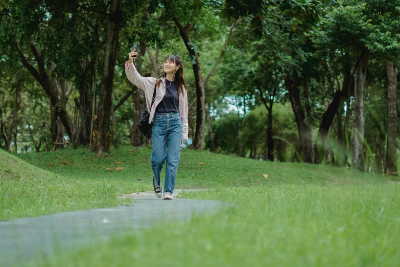 a woman walking down a path in a park, a picture, unsplash, happening, hold up smartphone, still from the movie, iu, joy ang