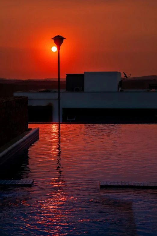 the sun is setting over a swimming pool, a portrait, inspired by Ricardo Bofill, unsplash, renaissance, sunset lighting 8k, square, backlighted, red reflective lens