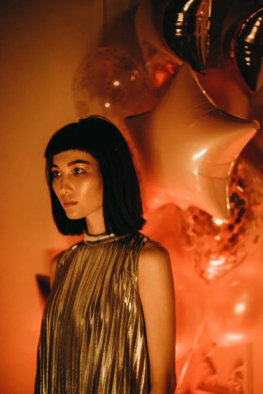 a woman standing in front of a bunch of balloons, an album cover, inspired by Elsa Bleda, trending on pexels, surrealism, black shiny bob haircut, gemma chan girl portrait, gold dappled lighting, holiday