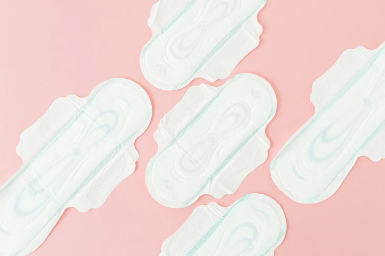 a group of sanitary pads sitting on top of a pink surface, detailed product image, arched back, 84mm), close-up on legs