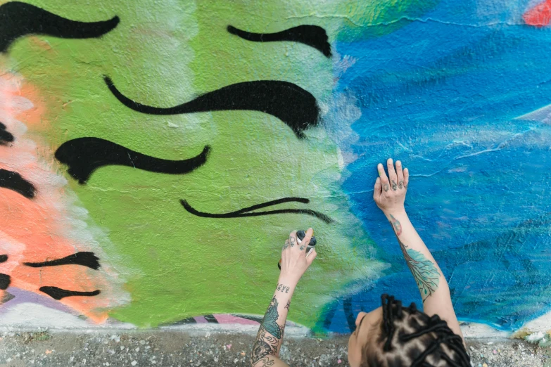 a woman painting a mural on the side of a building, trending on pexels, graffiti, bright green swirls coming up it, two hands reaching for a fish, avatar image, warpaint aesthetic