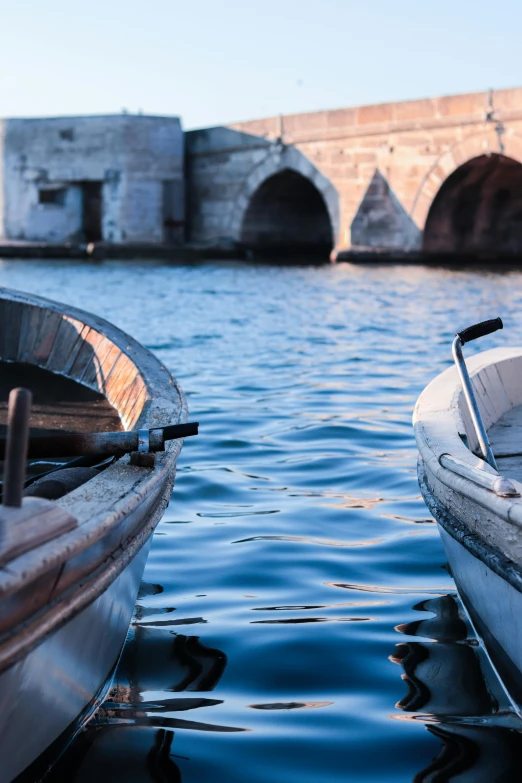 a couple of boats sitting on top of a body of water, by Carlo Martini, white stone arches, close up photograph