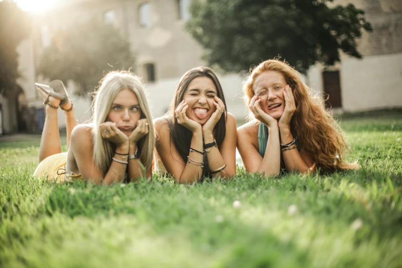 a group of women laying on top of a lush green field, pexels contest winner, making the best smug smile, avatar image, college, slightly tanned