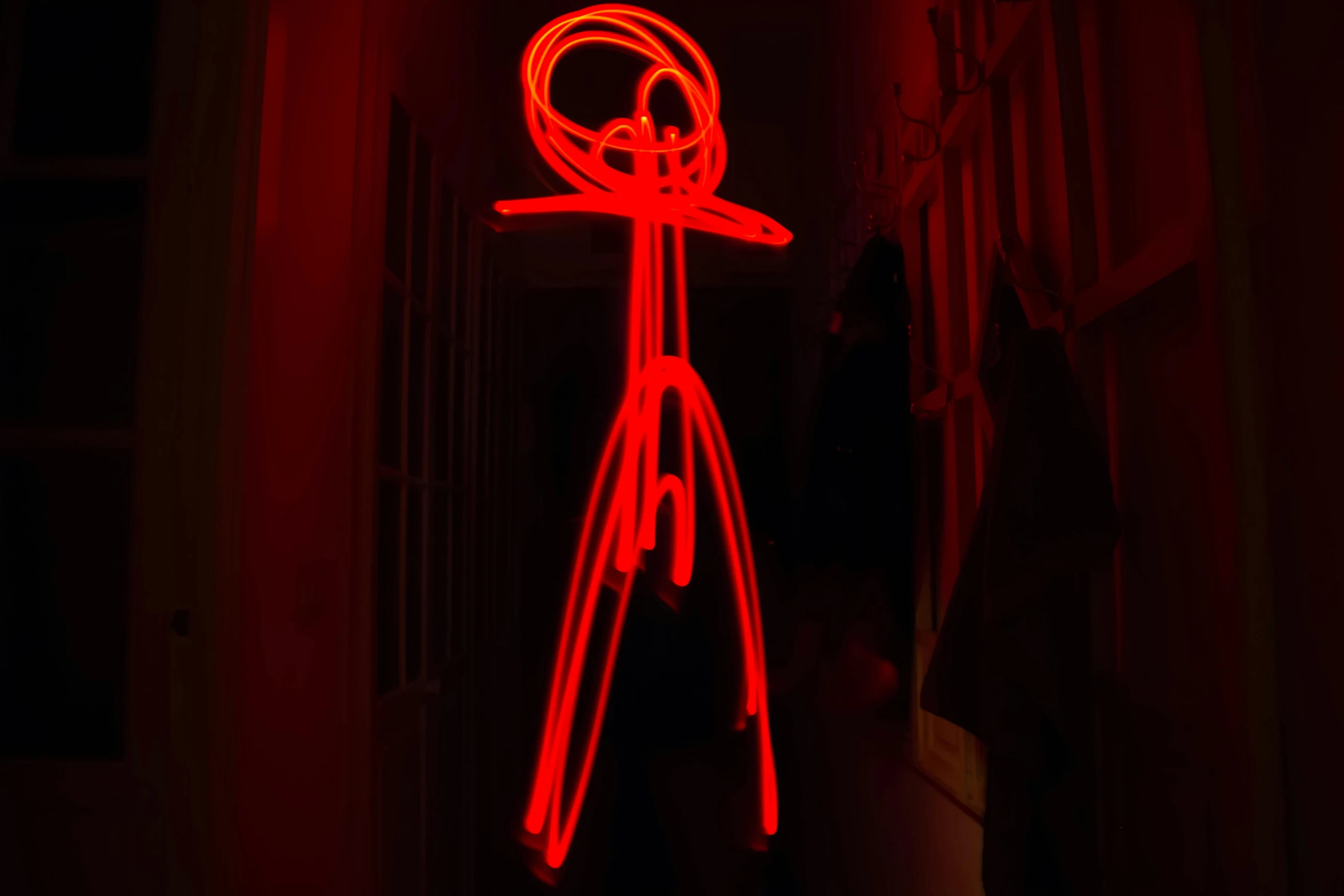 a person standing in a dark room with a red light, inspired by Bruce Nauman, graffiti, stick figure, photo taken in 2 0 2 0, wire sculpture drawings, taken on a 2010s camera