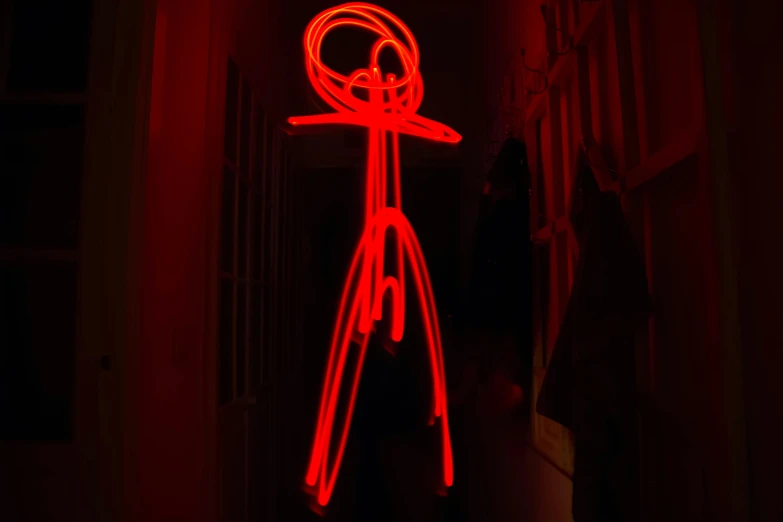 a person standing in a dark room with a red light, inspired by Bruce Nauman, graffiti, stick figure, photo taken in 2 0 2 0, wire sculpture drawings, taken on a 2010s camera