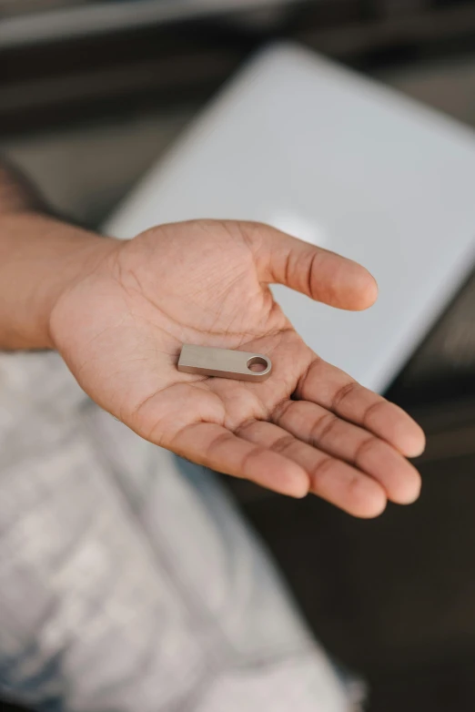 a person holding a small object in their hand, trending on pexels, made of brushed steel, rectangle, computer, amulet