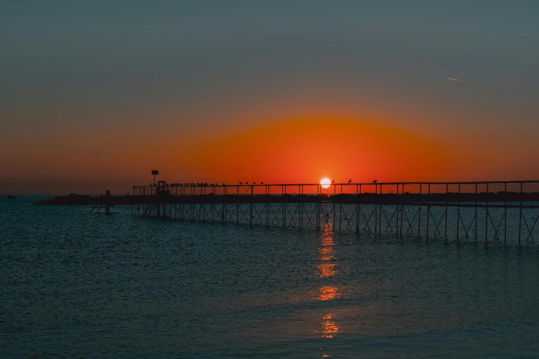 the sun is setting at the end of the pier, pexels contest winner, romanticism, photo taken from far away, 2022 photograph, medium long shot, no words 4 k