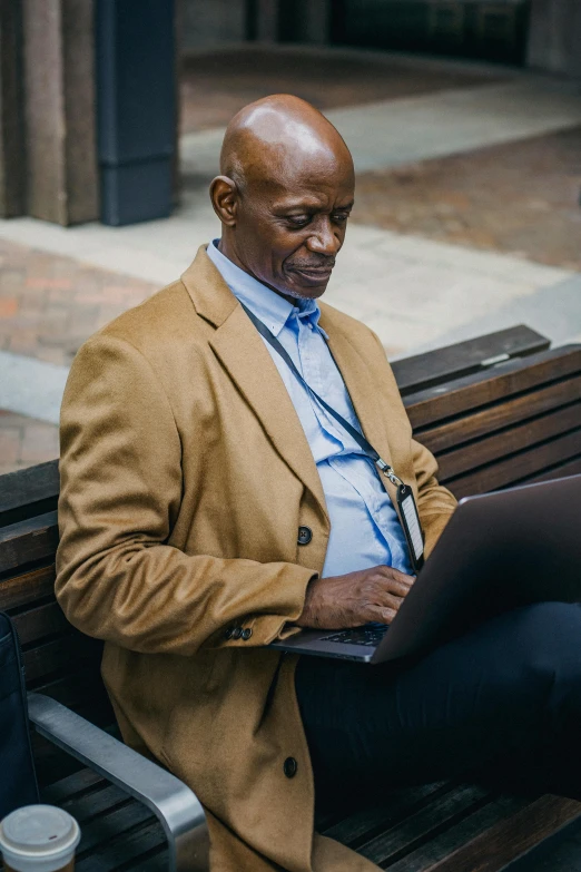 a man sitting on a bench using a laptop, atiba jefferson, the look of an elderly person, wearing a blue jacket, professional grade