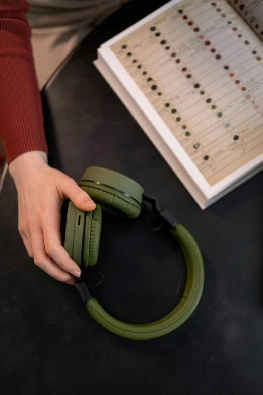 a person sitting at a table with headphones on, olive green, product image, closeup - view, cut-away