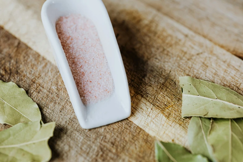 a white bowl sitting on top of a wooden table, pink, spices, detailed product image, epicurious