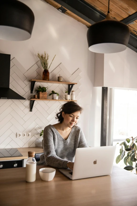 a woman sitting at a table working on a laptop, pexels contest winner, small kitchen, low quality photo, beautiful design, profile image