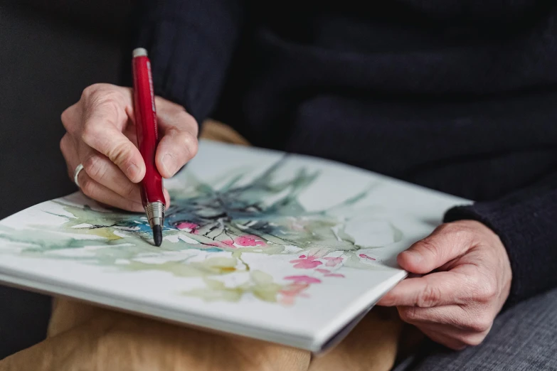 a person holding a pen and drawing on a piece of paper, a drawing, inspired by senior artist, pexels contest winner, botanic watercolors, traditional painting, artbook artwork, painted in high resolution