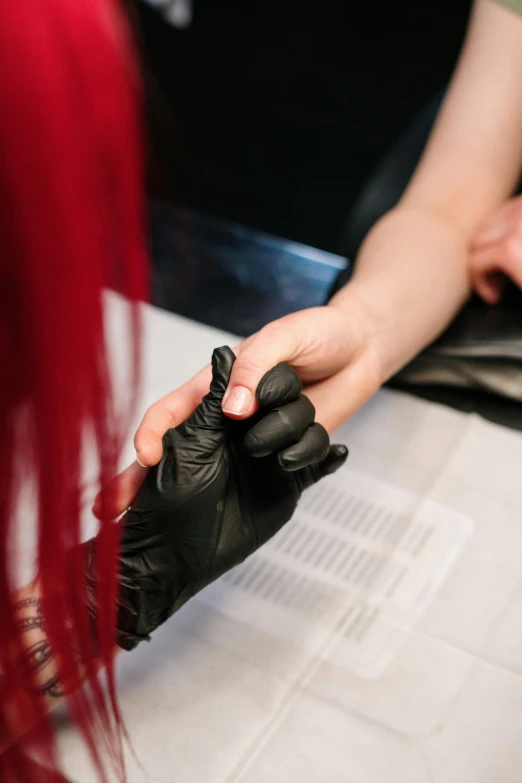 a woman getting her nails done at a salon, a tattoo, by Adam Marczyński, private press, black and red hair, closeup of hand, lgbtq, matte photo