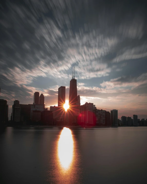 the sun is setting over a large body of water, a picture, by Jacob Burck, pexels contest winner, chicago, alternate album cover, multiple stories, backlighted