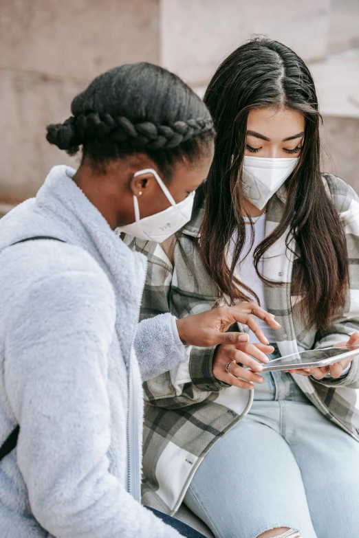 two women sitting on steps looking at a cell phone, trending on pexels, masked doctors, teenagers, grey, first aid kit