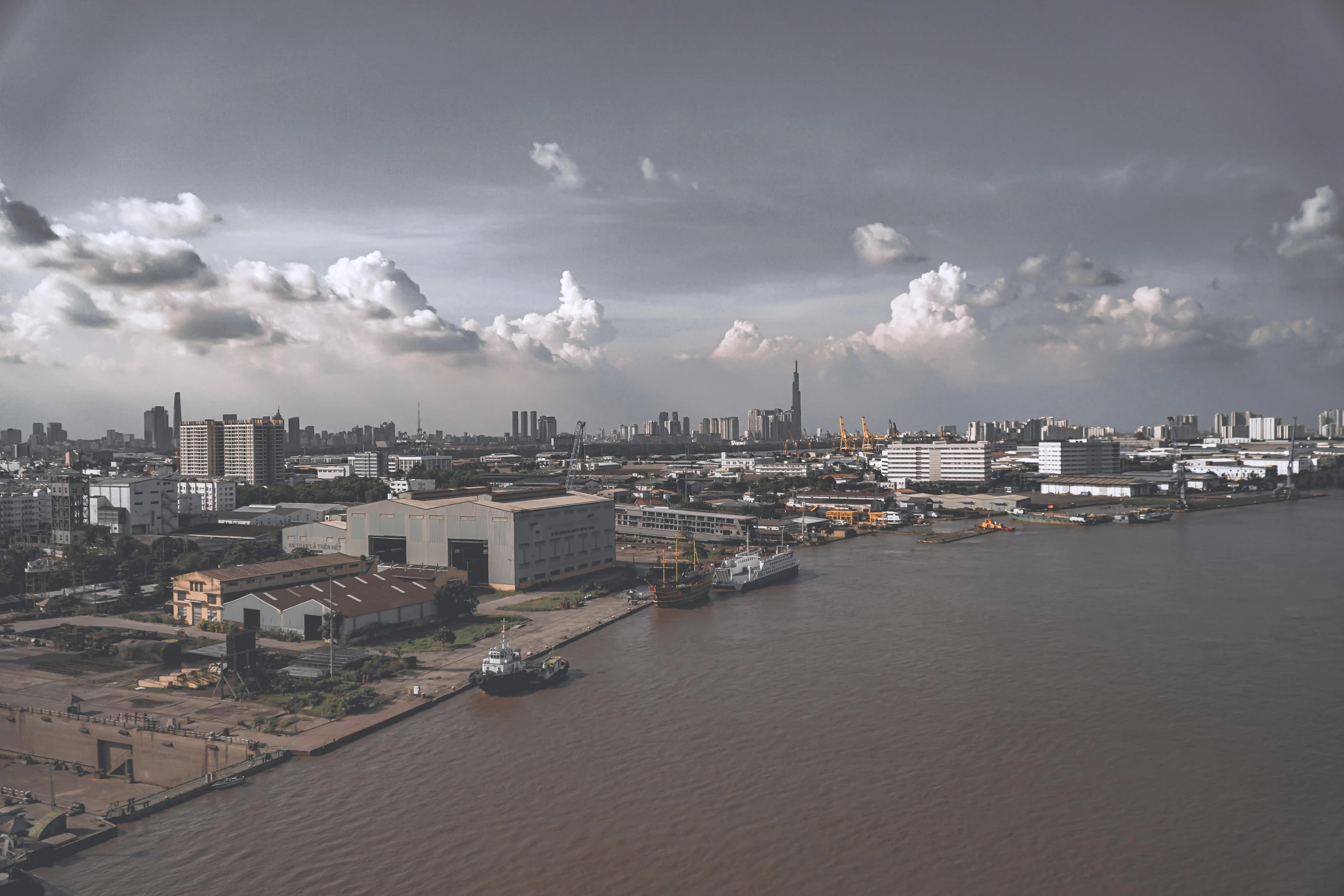 a large body of water with a city in the background, pexels contest winner, hyperrealism, shipyard, bangkok, desaturated, hd footage