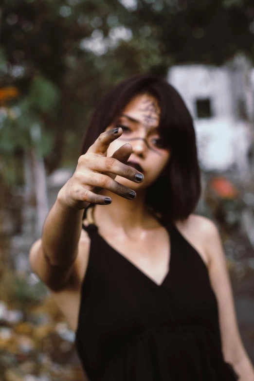 a woman taking a picture of herself with her cell phone, an album cover, inspired by Elsa Bleda, trending on pexels, gothic girl smoking, pointing index finger, young asian girl, black sclera