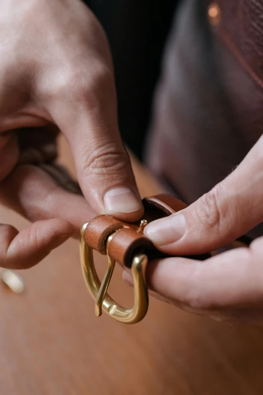 a close up of a person holding a pair of scissors, inspired by Paul Howard Manship, leather belt, rings, in a workshop, detailed product image